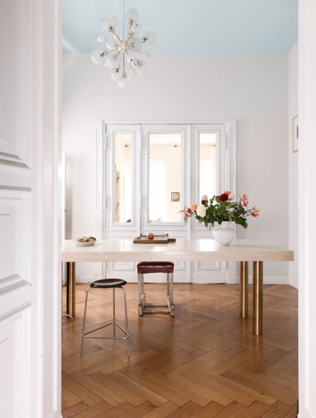 Comedor con gran ventanal y el techo pintado de azul suave.