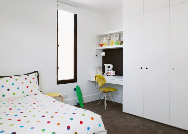 Dormitorio juvenil con el mobiliario diseñado a medida, el suelo continuo en un marrón que contrasta con los elementos blancos.