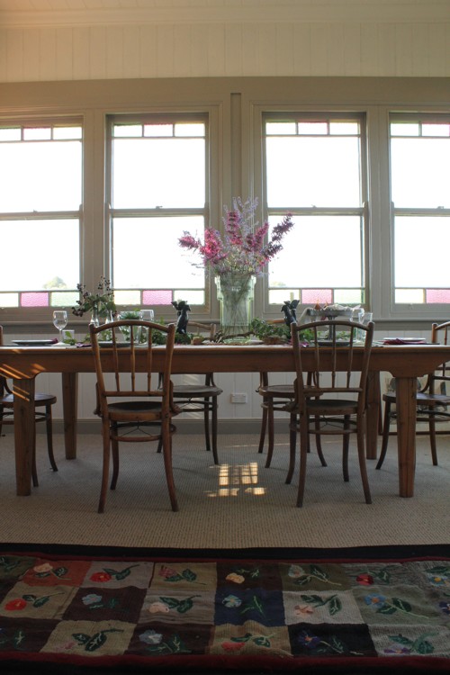 Comedor con una mesa muy grande y mucha luz que entra por las ventanas emplomadas.