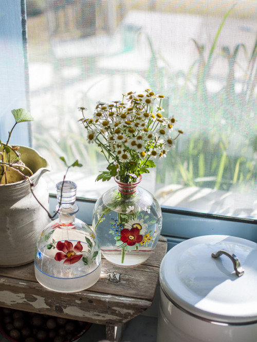 Detalle de las margaritas en la ventana dentro de jarrones pintados a mano.