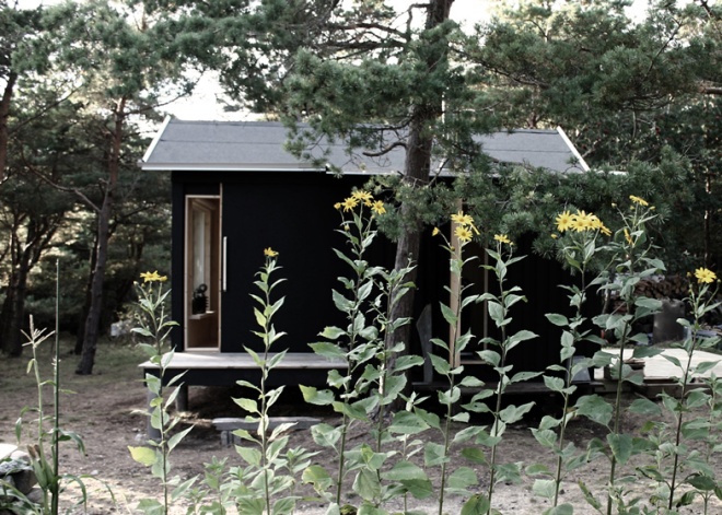 La cabaña está pintada de negro en su exterior y se mezcla muy bien con los colores del bosque.