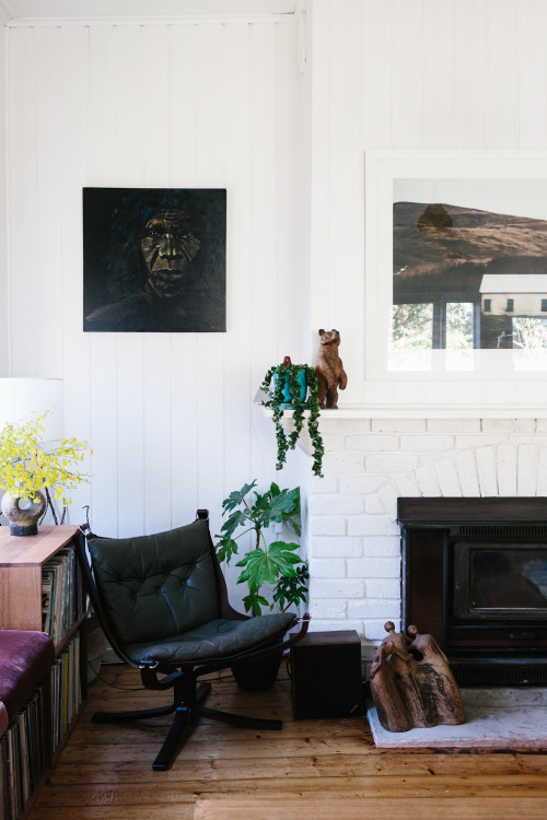 La zona de la chimenea, pintada de blanco con fotografías, plantas y mobiliario reciclado.