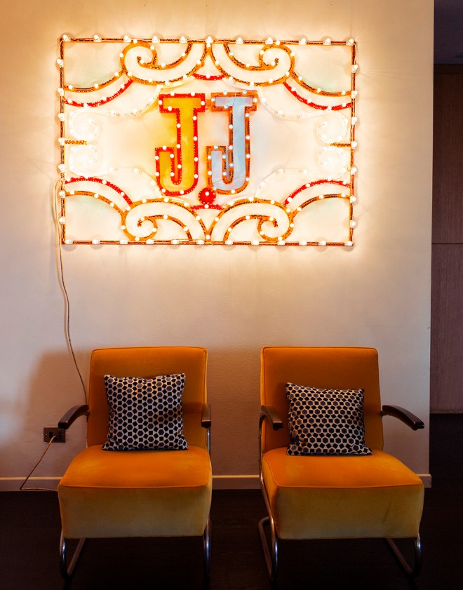 Pared con dos butacas con una composición también simétrica. El rótulo luminoso tiene las iniciales de la propietaria.